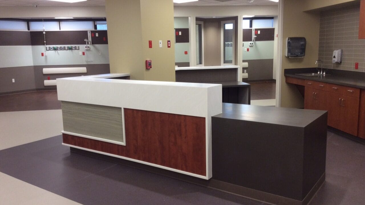 Modern hospital reception desk with wood and white accents in a spacious, well-lit waiting area.