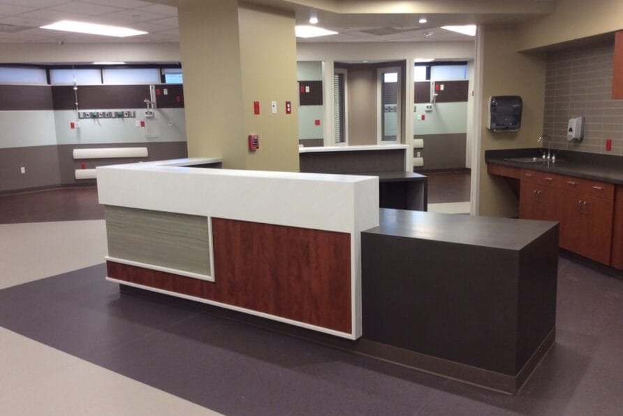 Modern hospital reception desk with wood and white accents in a spacious, well-lit waiting area.