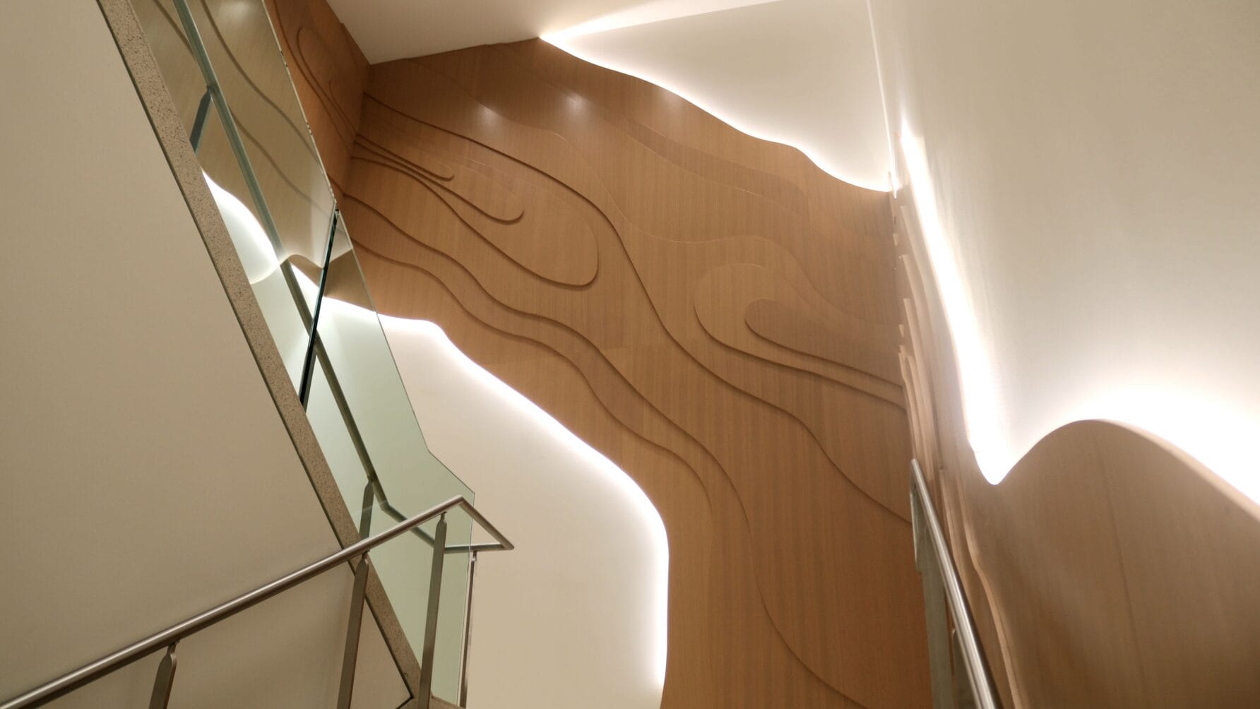 Staircase with modern wooden wall art featuring curved lines and ambient lighting