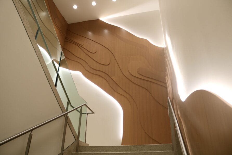 Staircase with modern wooden wall art featuring curved lines and ambient lighting