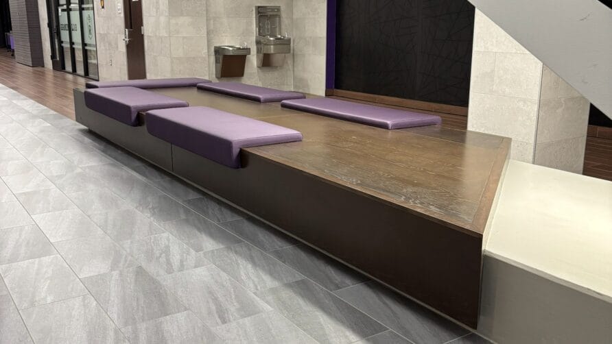 modern hallway with wooden benches and purple cushions under a staircase