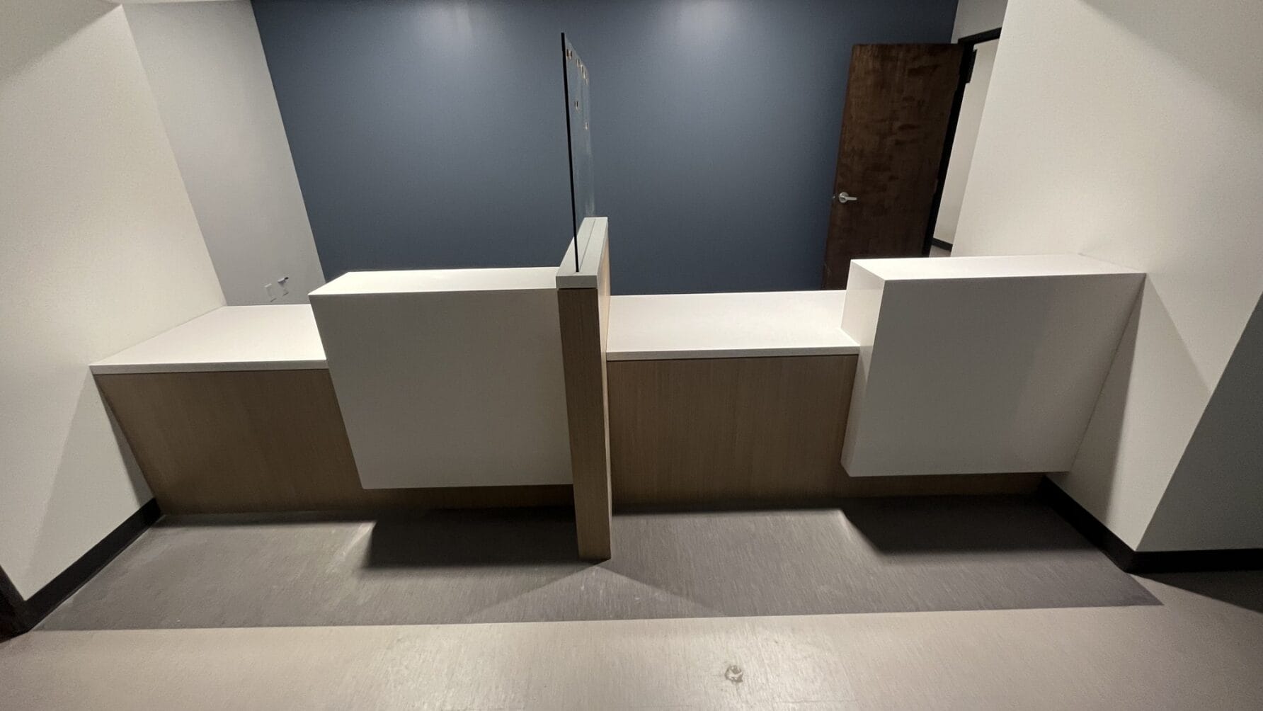 modern reception desk with divided sections in a room with blue accent wall and wooden door